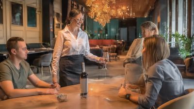 Eine sehr freundliche Kellnerin serviert den Gästen die Getränke am Tisch im Restaurant