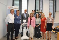 Staatssekretärin Nicole Steingaß (MWG RLP) rechts neben Roboter ‚Pepper‘ zusammen mit dem Projektteam und der Hochschulleitung  Quelle: Wassmann  Copyright: HWG LU